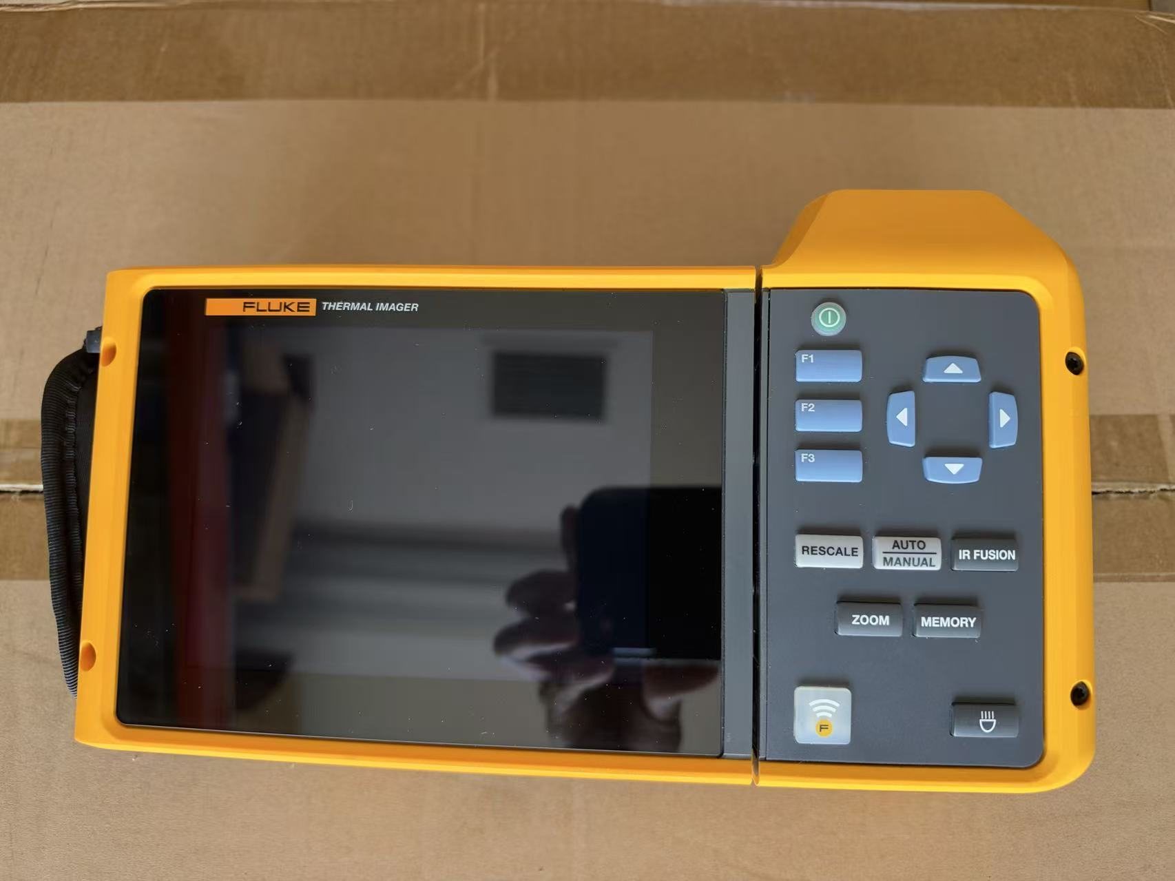 Fluke TiX580 thermal imager from the front: its touch screen beside the keypad with F1 to F3, arrows, Rescale, Auto/Manual, IR Fusion, Zoom and Memory keys